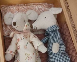 Eine Stoffmäuse-Ehepaar liegt in einer Schachtel, wie in einem Bett.